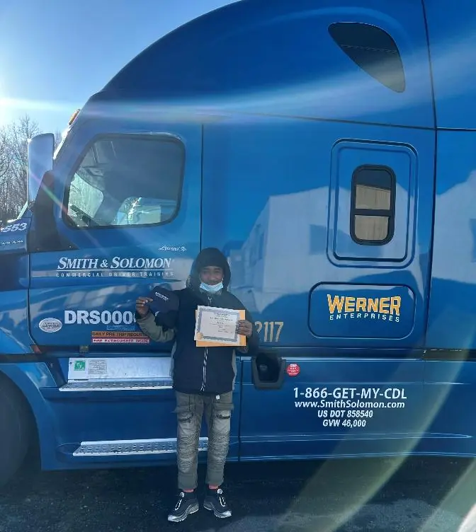 Basim Terry holding a professional certificate beside a commercial truck