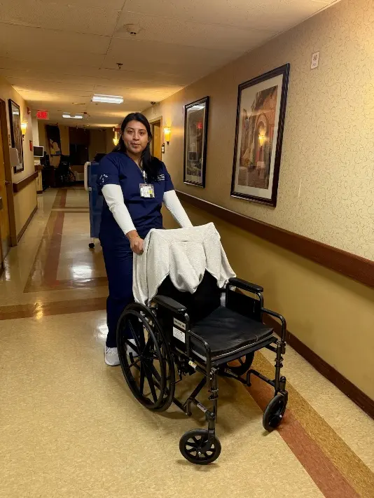 Berenise Rodriguez assisting with a wheelchair at Hudson View Nursing and Rehab Center