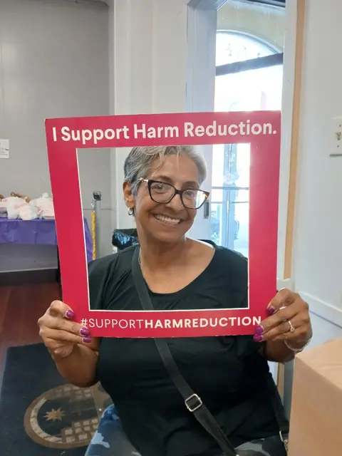 Emely Rolon holding an I Support Harm Reduction frame