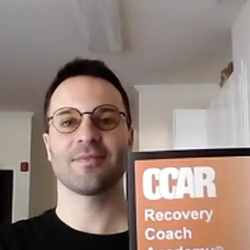 Phillip Mastrotto holding a CCAR Recovery Coach Academy guide